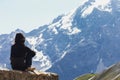 A young woman sits on a rock and looks at the mountains. View from the back of a man looking at the Swiss Alps Royalty Free Stock Photo