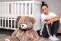 Young woman sits sad by the crib. Postpartum Depression Concept Royalty Free Stock Photo