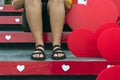 A young woman sits on the stairs with beautiful red and white heart made of corrugated plastic decorated on the stairs on occasion