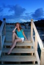 Young woman sits on steps at descent to the sea at night. Maldives. Royalty Free Stock Photo