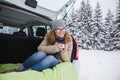 Young woman sits in the trunk of the car and holds a cup of hot tea Royalty Free Stock Photo