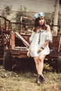 Young Woman Sitting On Abandoned Vehicle At Field