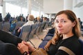 Young woman sitting at airport hall, looking tired after waiting couple of hours for connecting flight in early morning, more Royalty Free Stock Photo