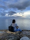 Young woman sitting alone on the beach watching the sea view. Blue sky over the ocean horizon. Tranquil nature scenery. Self love Royalty Free Stock Photo