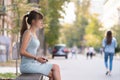 Young woman sitting alone on city street outdoors waiting for someone to arrive. Arriving late on business meeting Royalty Free Stock Photo