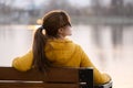 Young woman sitting alone on park bench relaxing on warm autumn day