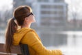 Young woman sitting alone on park bench relaxing on warm autumn day