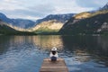 Young woman sitting alone on wooden pier, looking lake and mountain view in summer at Hallstatt, Austria