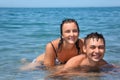 Young woman sitting astride man in sea near coast