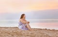 Young woman sitting on the beach at coast enjoying sea Royalty Free Stock Photo