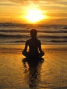 Young woman sitting on the beach, silhouette at sunset. Young woman practicing yoga outdoors. Harmony and meditation concept. Royalty Free Stock Photo