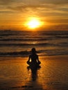 Young woman sitting on the beach, silhouette at sunset. Young woman practicing yoga outdoors. Harmony and meditation concept. Royalty Free Stock Photo