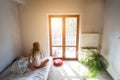 Young woman sitting on bed and looking through the window. Royalty Free Stock Photo