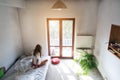 Young woman sitting on bed and looking through the window. Royalty Free Stock Photo