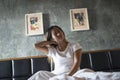 Young woman sitting on the bed with neck pain after Royalty Free Stock Photo