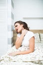 Young woman sitting on the bed with pain in neck at home Royalty Free Stock Photo