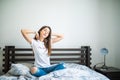 Young woman sitting in bed and strech her body at home