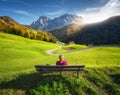 Young woman sitting on the bench and beautiful alpine village