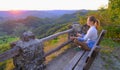 Young woman sitting on a bench on a hill and meditating during sunrise in the mountains. Relax, inspiration, meditation, travel co