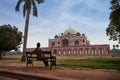Young woman sitting at a bench and lookin to Humayun`s tomb in Delhi, India.
