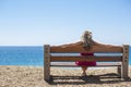 Young woman sitting on a bench and looking at the sea Royalty Free Stock Photo