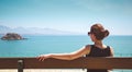 Young woman sitting on a bench and looking at the sea Royalty Free Stock Photo