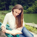 Young woman sitting on the bench and reading book Royalty Free Stock Photo