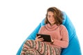 Young woman sitting on blue beanbag chair and holding a tablet i Royalty Free Stock Photo