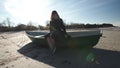 Young woman sitting in a boat on the beach in sunny weather on the Baltic Sea dancing and filling silly