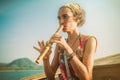 Young woman sitting on boat and playing bamboo flute Royalty Free Stock Photo