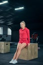 Young woman sitting on a box at gym after her workout and looking at the camera. Royalty Free Stock Photo