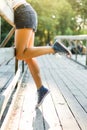 Young woman sitting on a bridge railing in jeans sneakers