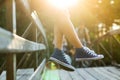 Young woman sitting on a bridge railing in jeans sneakers