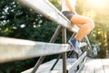 Young woman sitting on a bridge railing in jeans sneakers Royalty Free Stock Photo