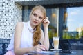 Young woman sitting at cafe, drinking coffee and making notes in notebook Royalty Free Stock Photo