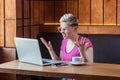 Young woman is sitting in cafe and having bad mood are admonishing a worker through a webcam with raised arms Royalty Free Stock Photo