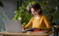 Young woman sitting at cafe, taking notes in notebook Royalty Free Stock Photo