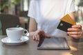 Young woman sitting in cafe and using modern tablet and credit card Royalty Free Stock Photo