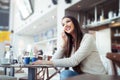 Young woman sitting in the cafeteria with laptop and using mobile phone Royalty Free Stock Photo