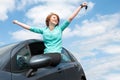 Young woman sitting in the car and holding a key against blue sk Royalty Free Stock Photo