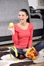 Young woman sitting on carpet and enjoying fruits