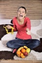 Young woman sitting on carpet and enjoying fruits