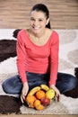 Young woman sitting on carpet and enjoying fruits