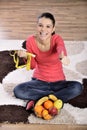 Young woman sitting on carpet and enjoying fruits