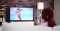 Young Woman Sitting On Carpet Watching Movie On Television