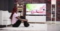 Young Woman Sitting On Carpet Watching Movie On Television