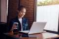 Young woman sitting on chair at coffee shop  while working on laptop Royalty Free Stock Photo