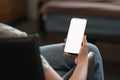 Young woman sitting in chair with modern smartphone with white screen