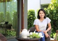 Young woman sitting on chair and Tea set on rattan Furniture in the garden Royalty Free Stock Photo