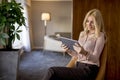 Blonde woman sitting on chair and using digital tablet Royalty Free Stock Photo